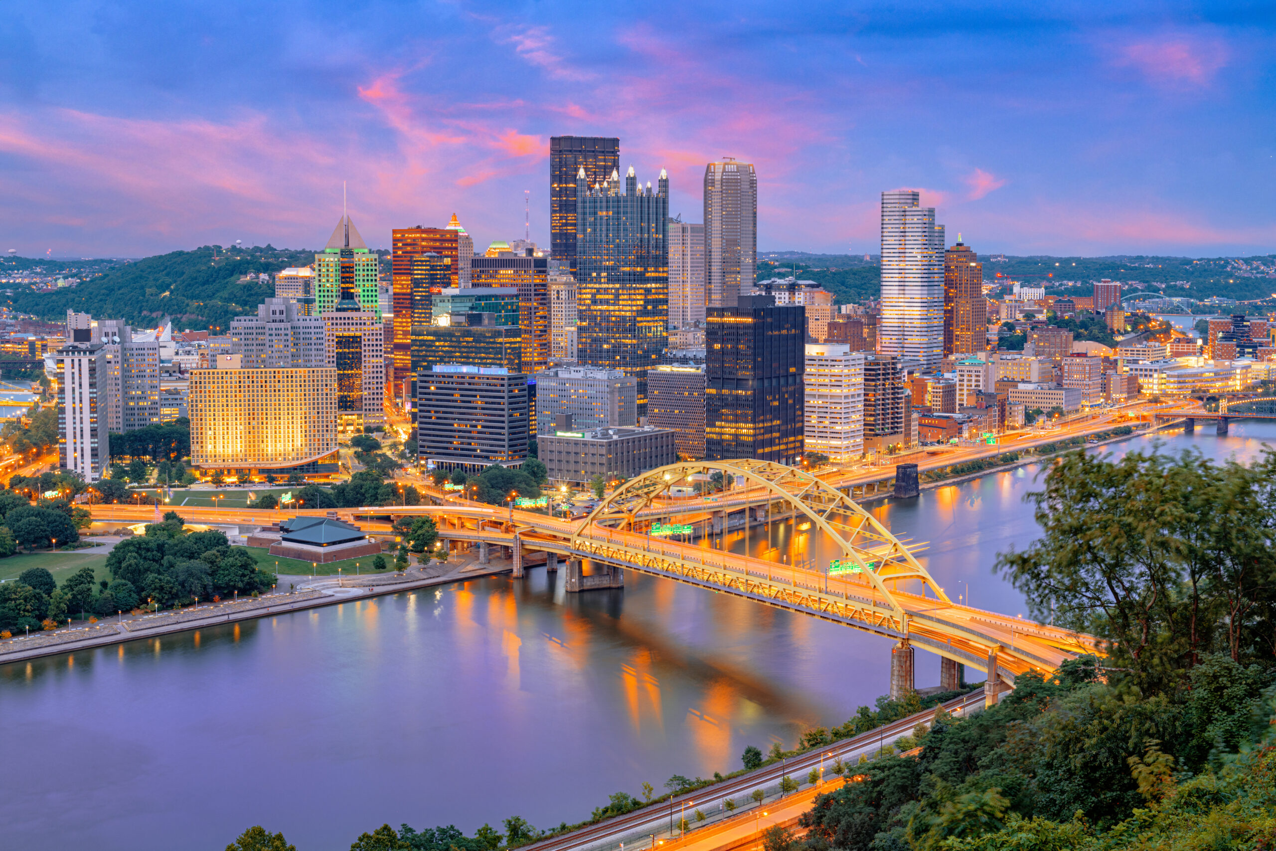 Pittsburgh, Pennsylvania, USA City Skyline A realistic aerial view of a New Jersey cityscape featuring a busy street with cars driving and parked along the side. The scene includes a mix of mod.webp